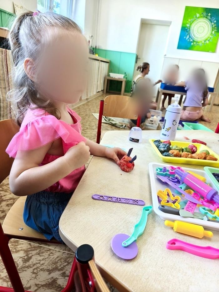 Holčička modeluje z barevné modelíny u stolečku